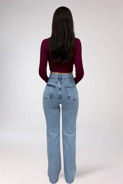 Person wearing a burgundy top and light blue jeans on a white background