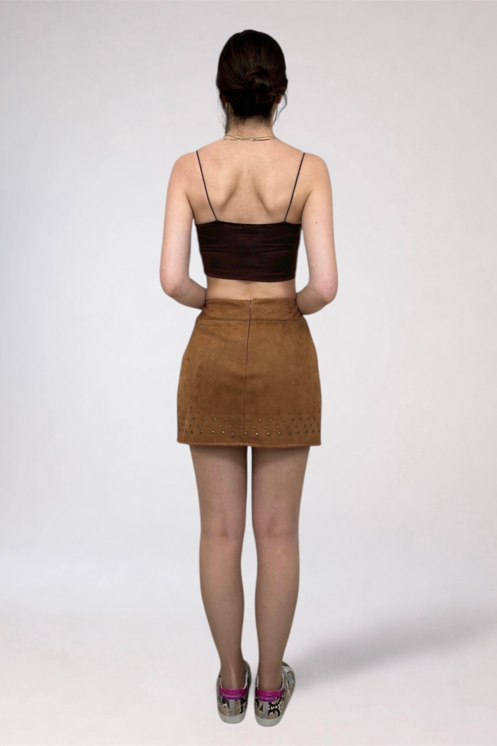 Person wearing a brown top and skirt on a white background