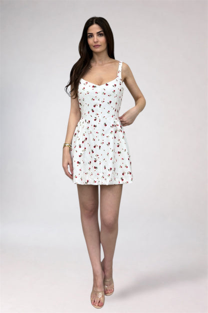 Woman wearing a white dress with red floral pattern on a plain background