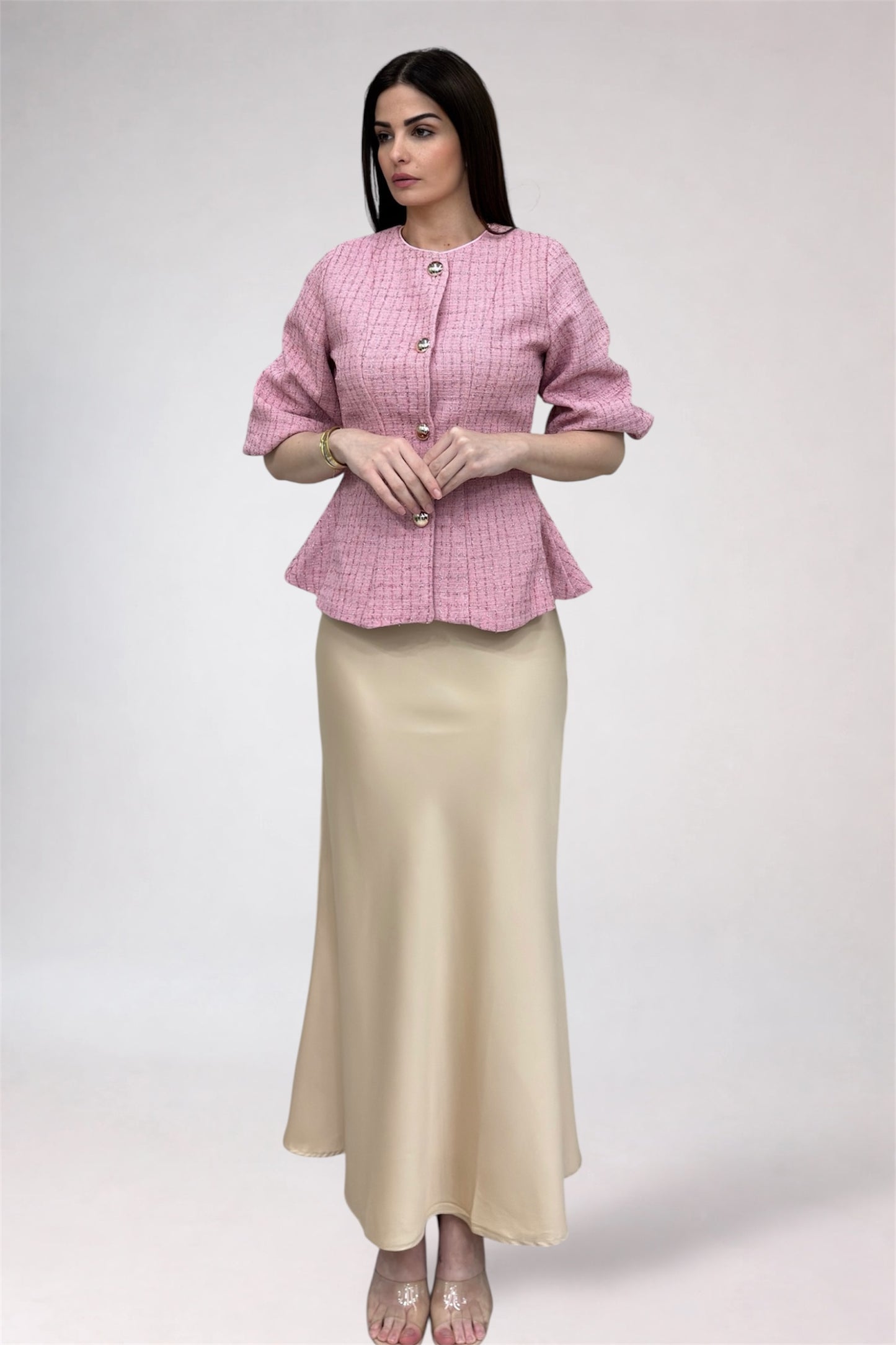 Woman wearing a pink checkered top and beige skirt on a white background