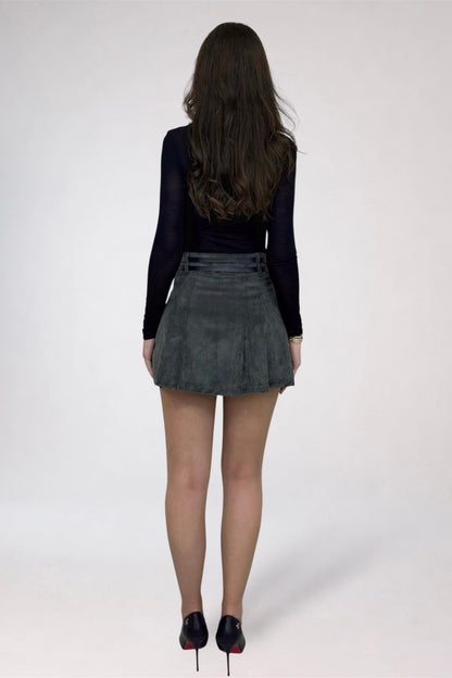 Person wearing a black top and gray pleated skirt on a white background
