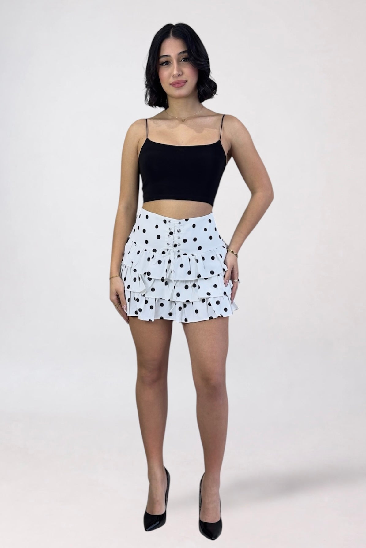 Woman wearing a black top and white polka dot skirt on a white background