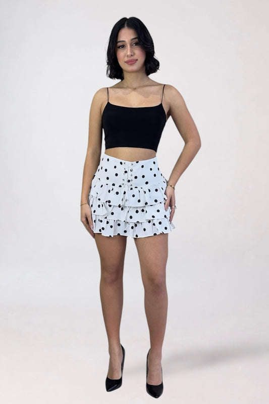 Woman wearing a black top and white polka dot skirt on a white background
