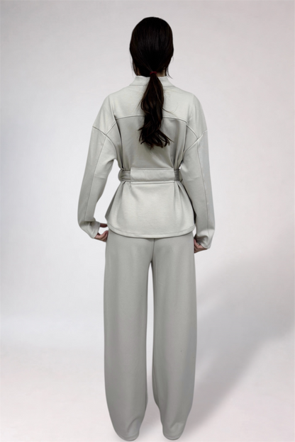 Person wearing a light gray outfit with a belt on a white background
