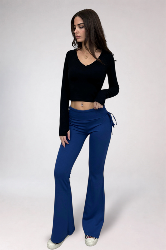 Woman wearing a black top and blue flared pants on a white background