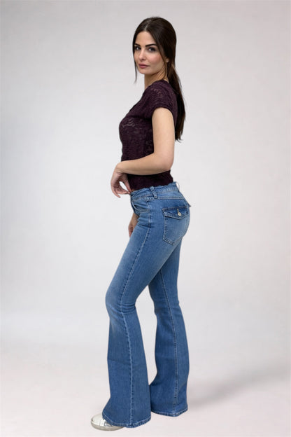 Woman wearing a dark top and blue flared jeans on a white background