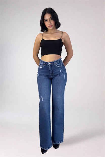 Woman wearing blue jeans and a black top on a white background