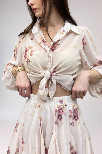 Woman wearing a floral blouse and skirt set against a plain background