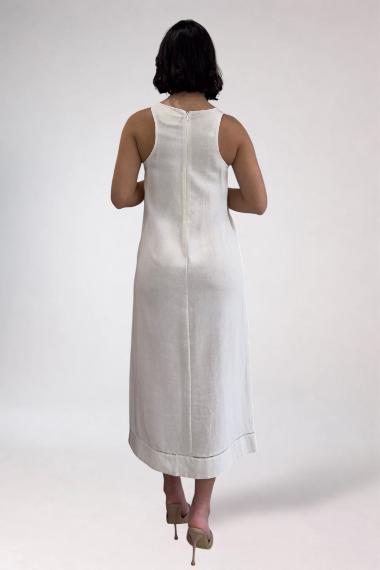 Woman wearing a white sleeveless dress on a plain background