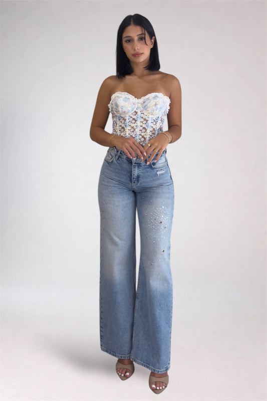 Woman wearing a floral top and blue jeans on a white background