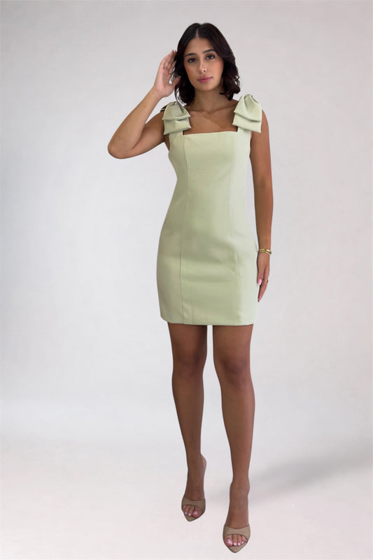Woman wearing a light green dress with a bow detail on a white background
