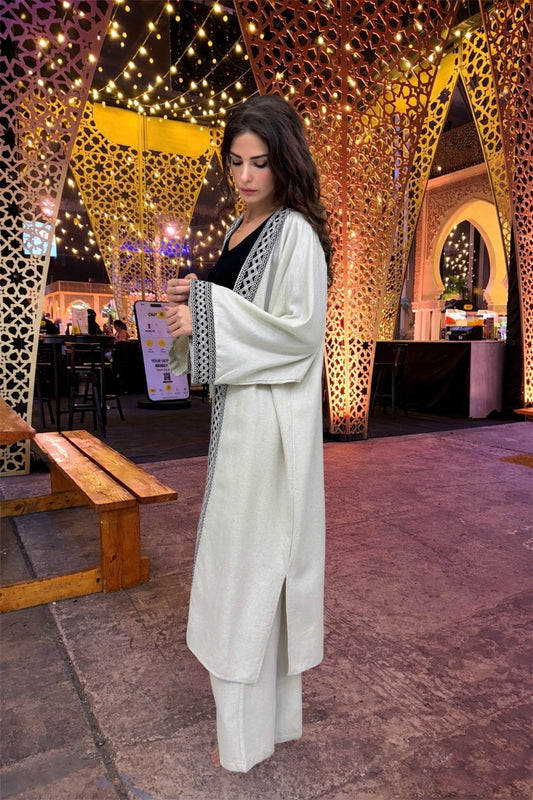 Woman in a white outfit standing in an outdoor setting with decorative lights and arches.