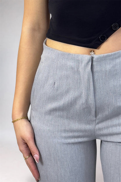 Person wearing light gray pants and a black top on a plain background