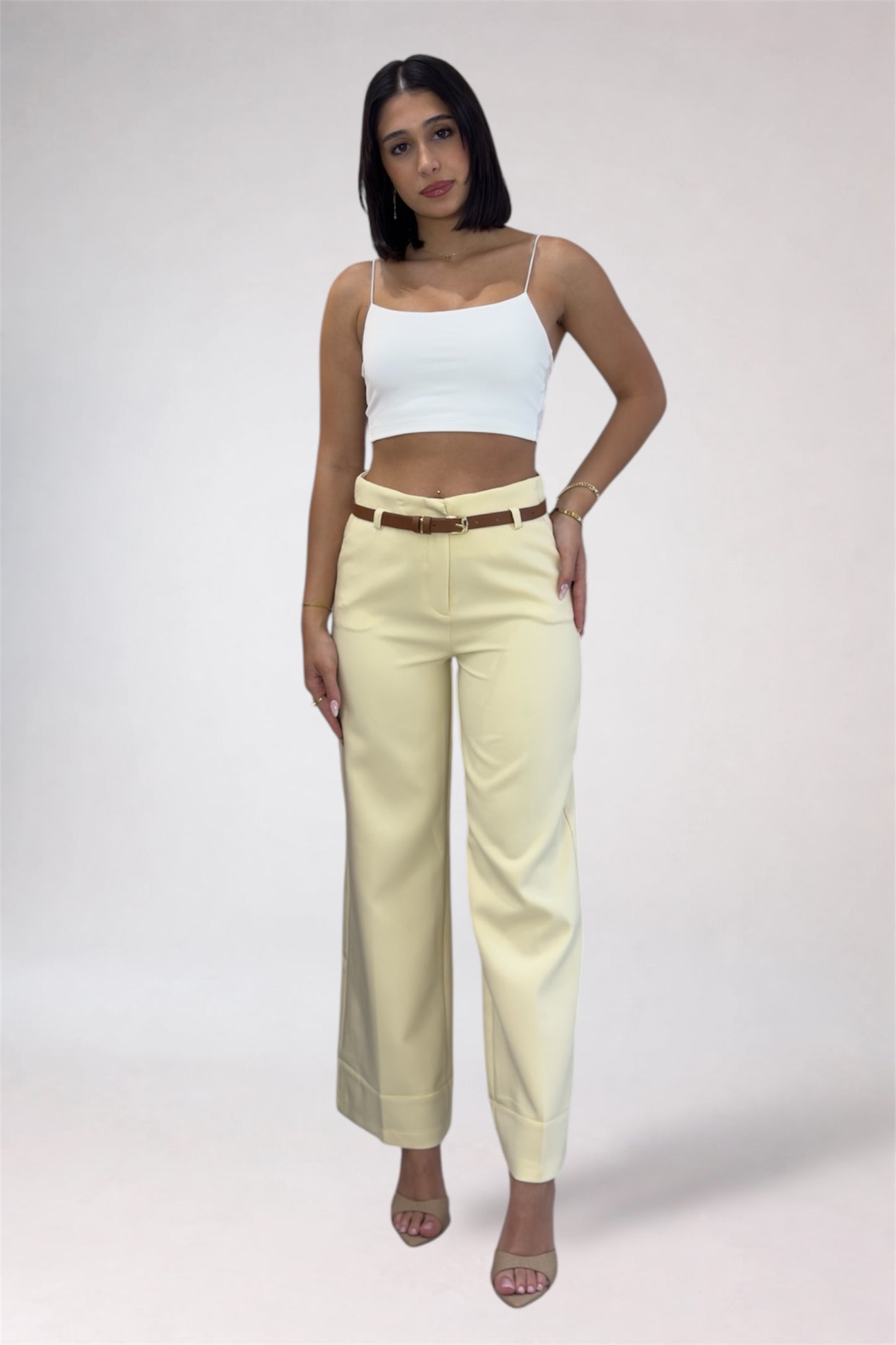 Woman wearing a white top and yellow pants on a plain background