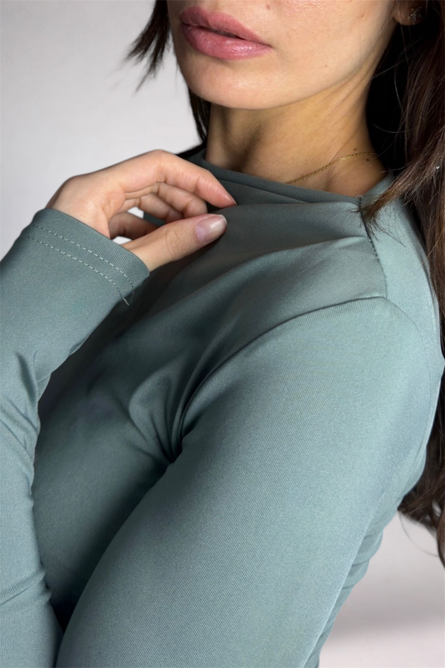 Close-up of a person wearing a light blue long-sleeve shirt against a neutral background