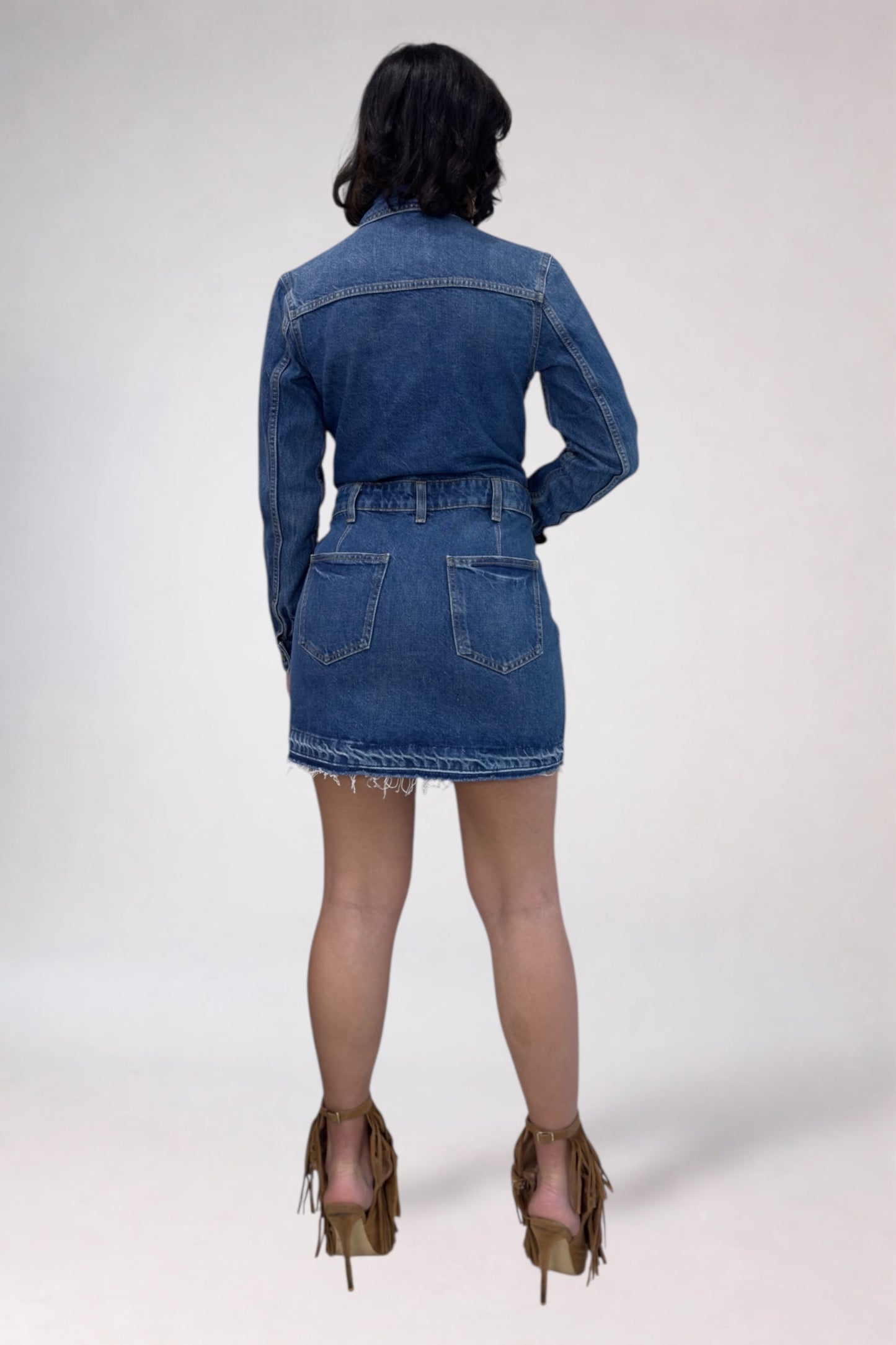 Person wearing a blue denim jacket and skirt on a white background