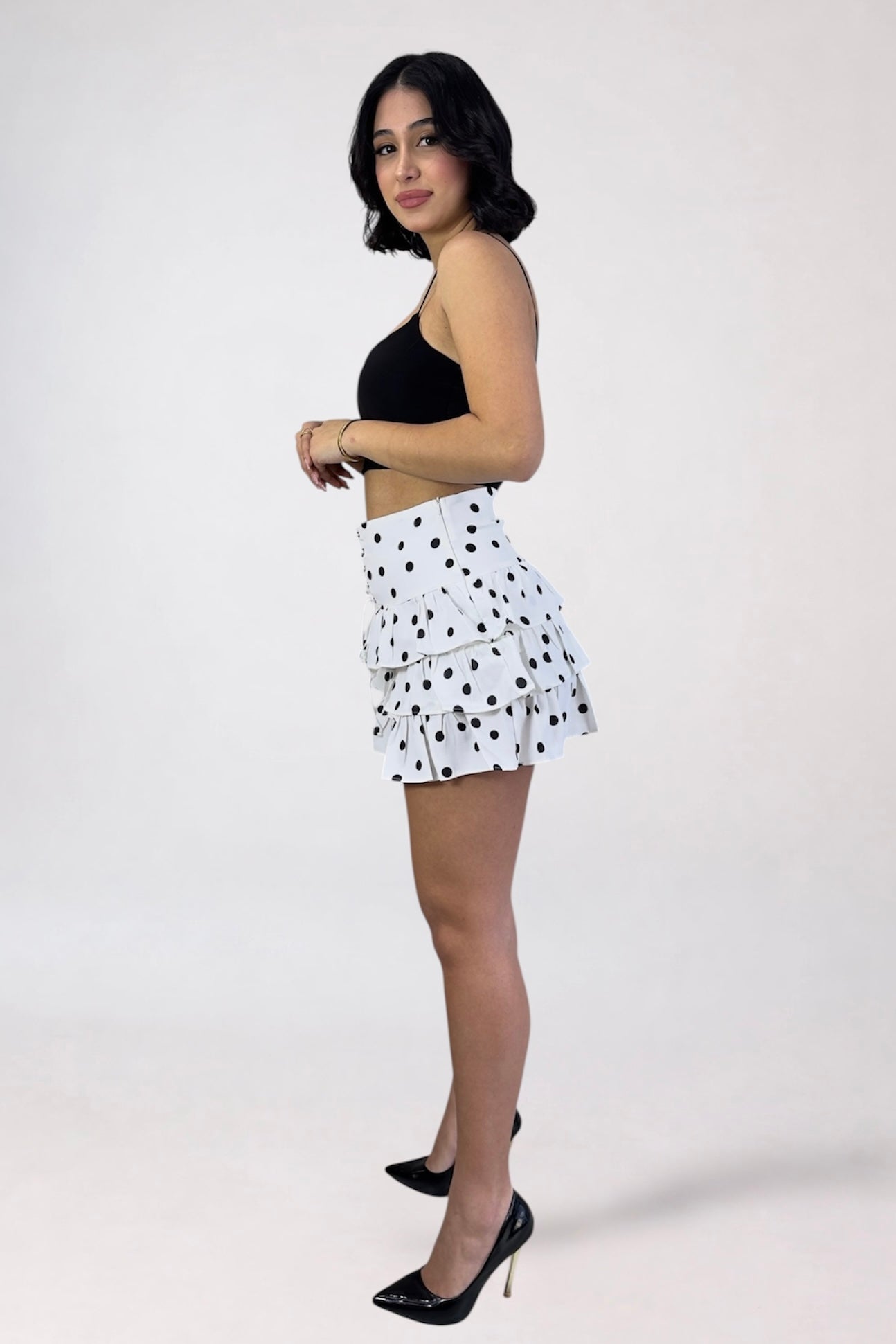 Woman wearing a black top and white polka dot skirt on a white background