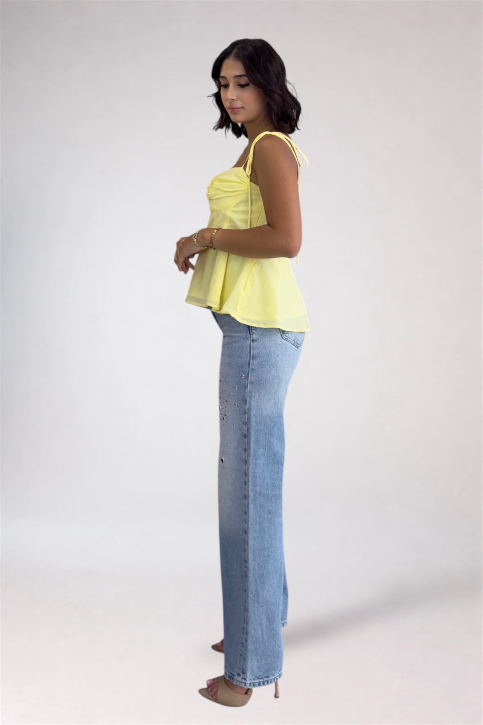 Woman wearing a yellow top and blue jeans on a white background