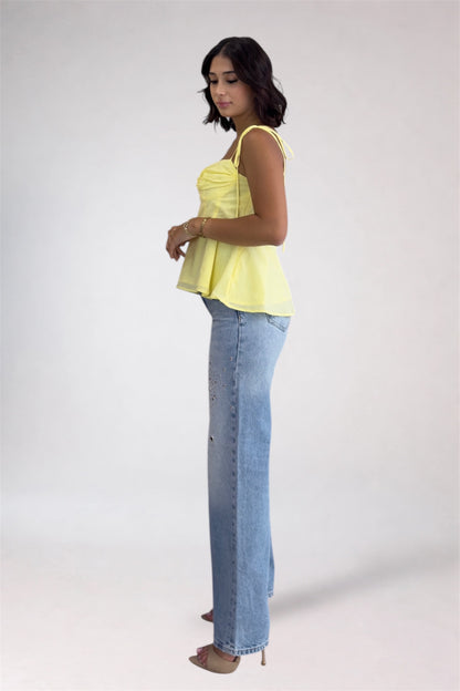 Woman wearing a yellow top and blue jeans on a white background