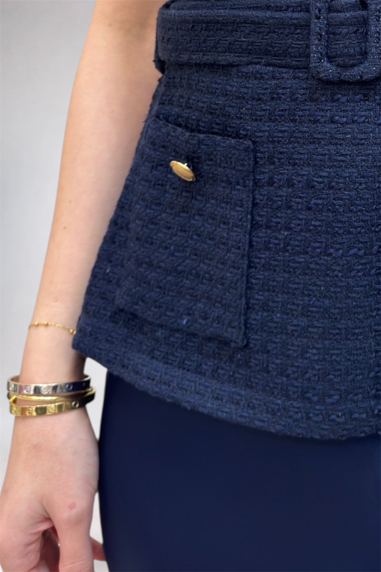 Navy blue textured skirt with a gold button on a neutral background