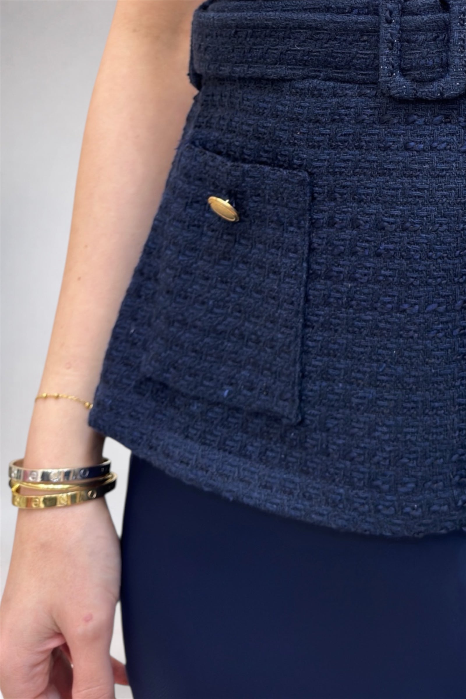 Navy blue textured skirt with a gold button on a neutral background