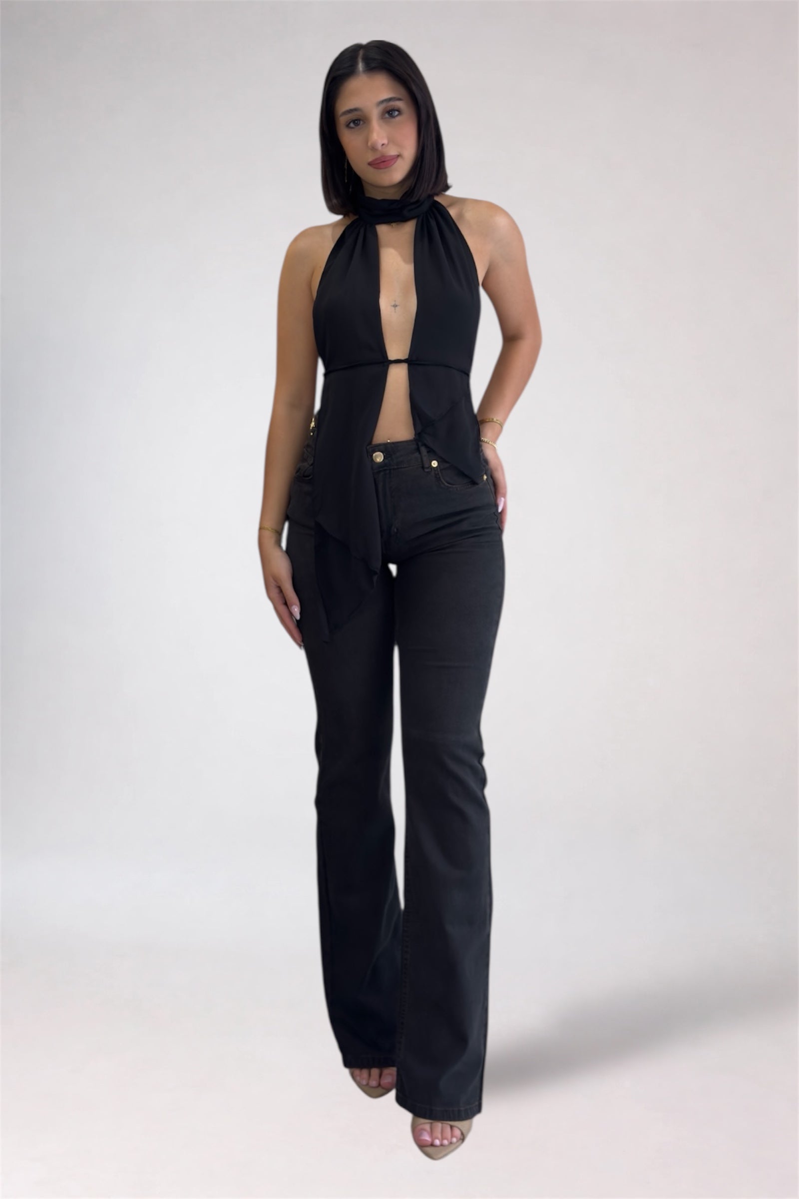 Woman wearing a black sleeveless top and high-waisted black pants on a white background