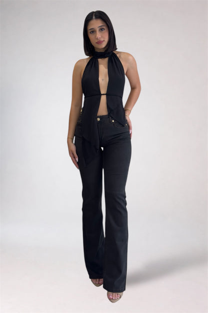 Woman wearing a black sleeveless top and high-waisted black pants on a white background
