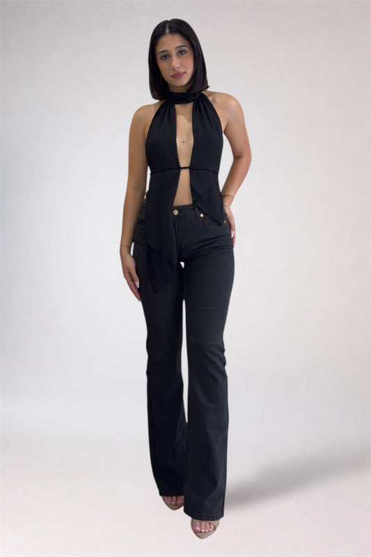 Woman wearing a black sleeveless top and high-waisted black pants on a white background