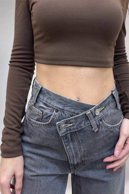 Person wearing a brown long-sleeve top and blue jeans against a neutral background