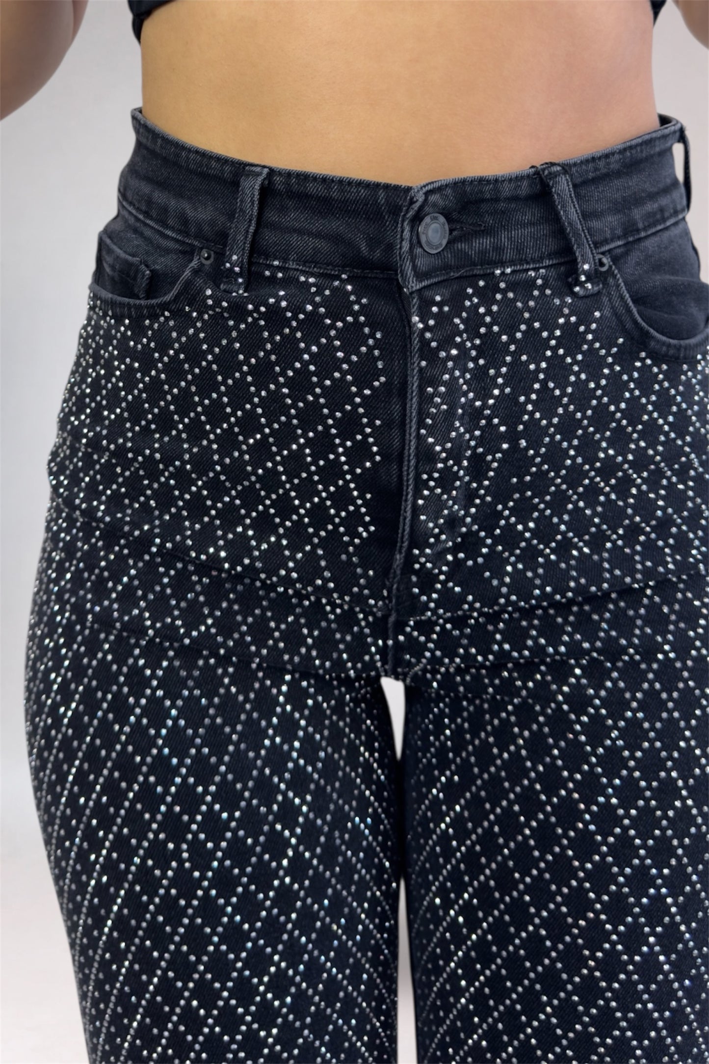Black patterned jeans worn by a person on a white background