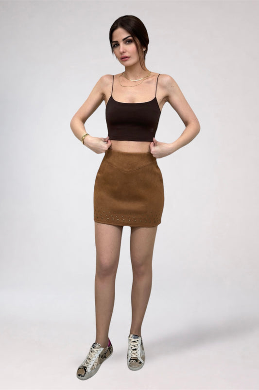 Woman wearing a black crop top and brown skirt on a white background