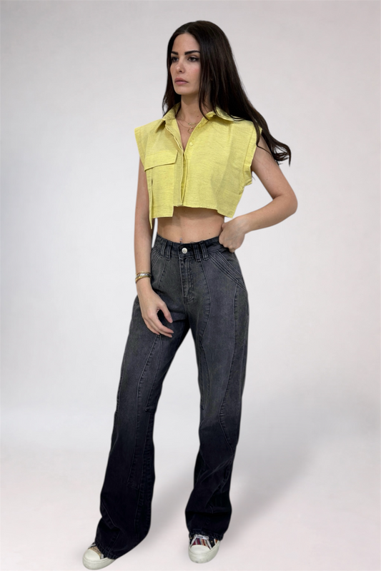 Woman wearing a yellow sleeveless top and black jeans on a white background