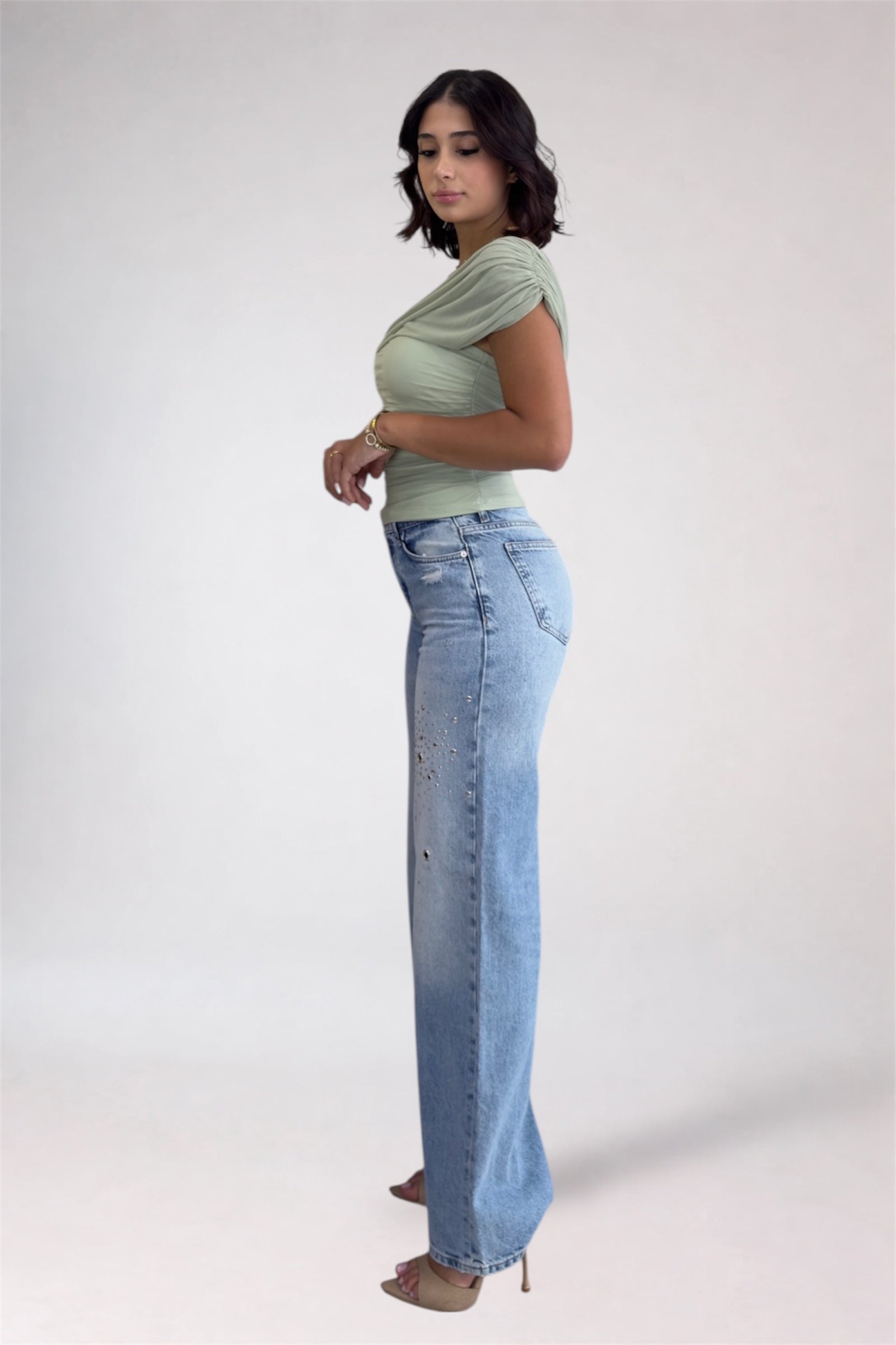 Woman wearing a green top and blue jeans on a white background