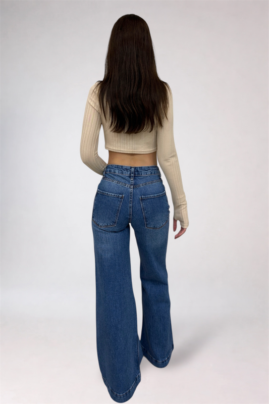 Person wearing blue jeans and a beige top on a white background