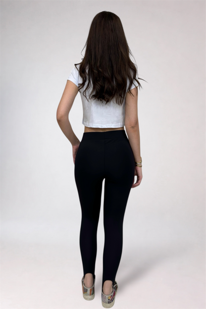 Person wearing a white crop top and black leggings on a plain background