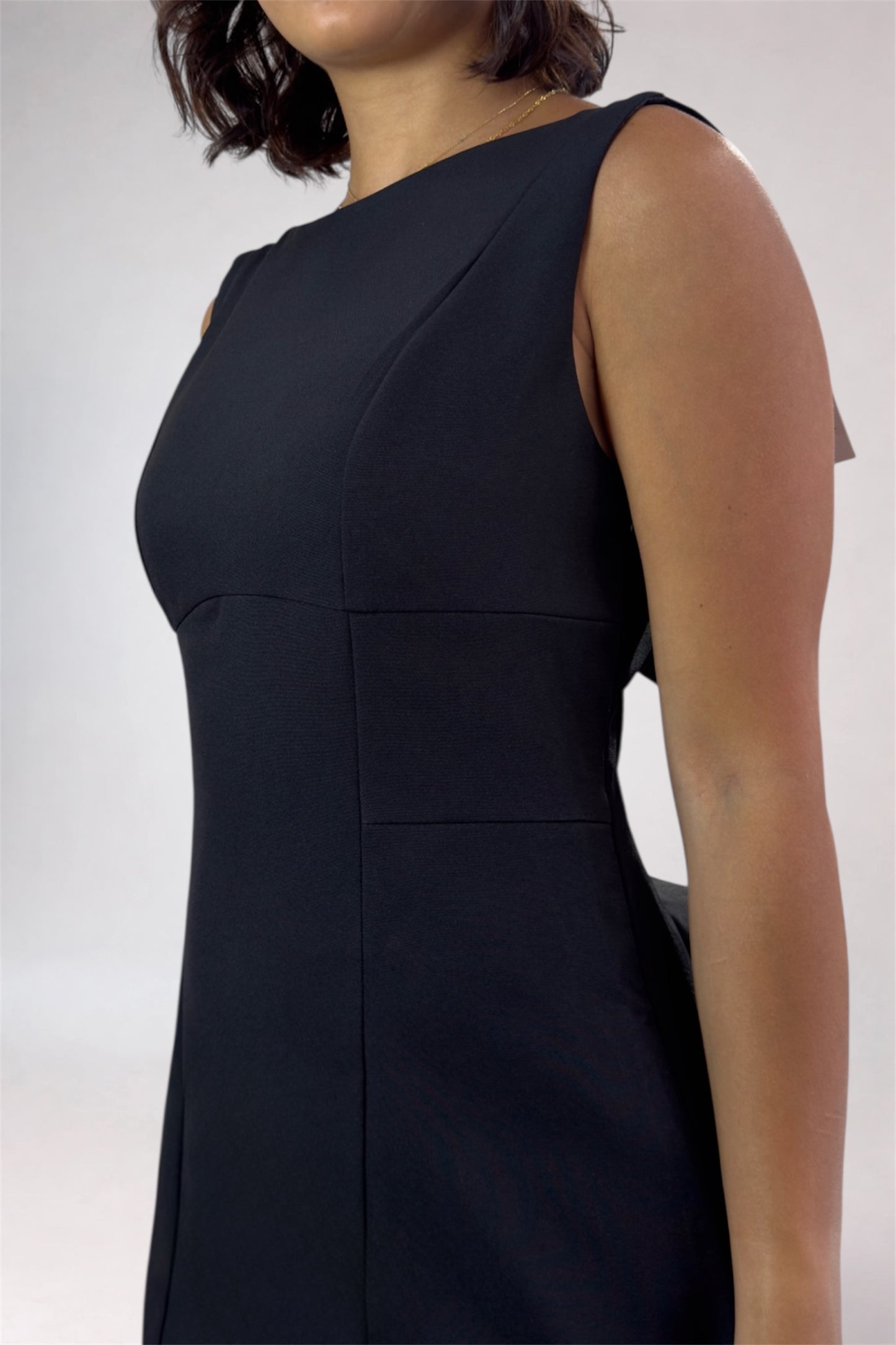 Black sleeveless dress worn by a person on a white background