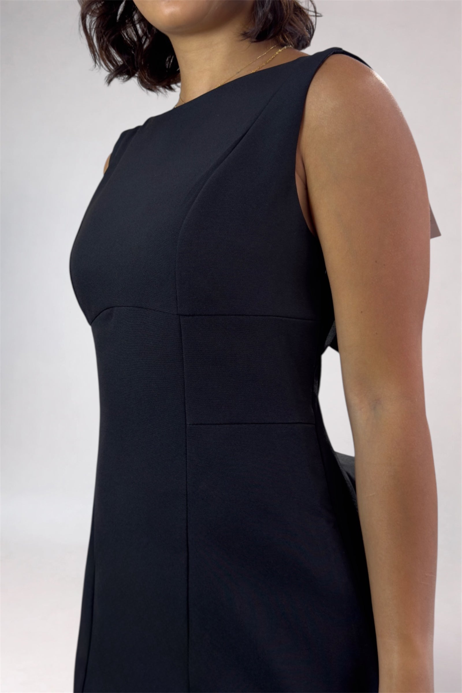 Black sleeveless dress worn by a person on a white background