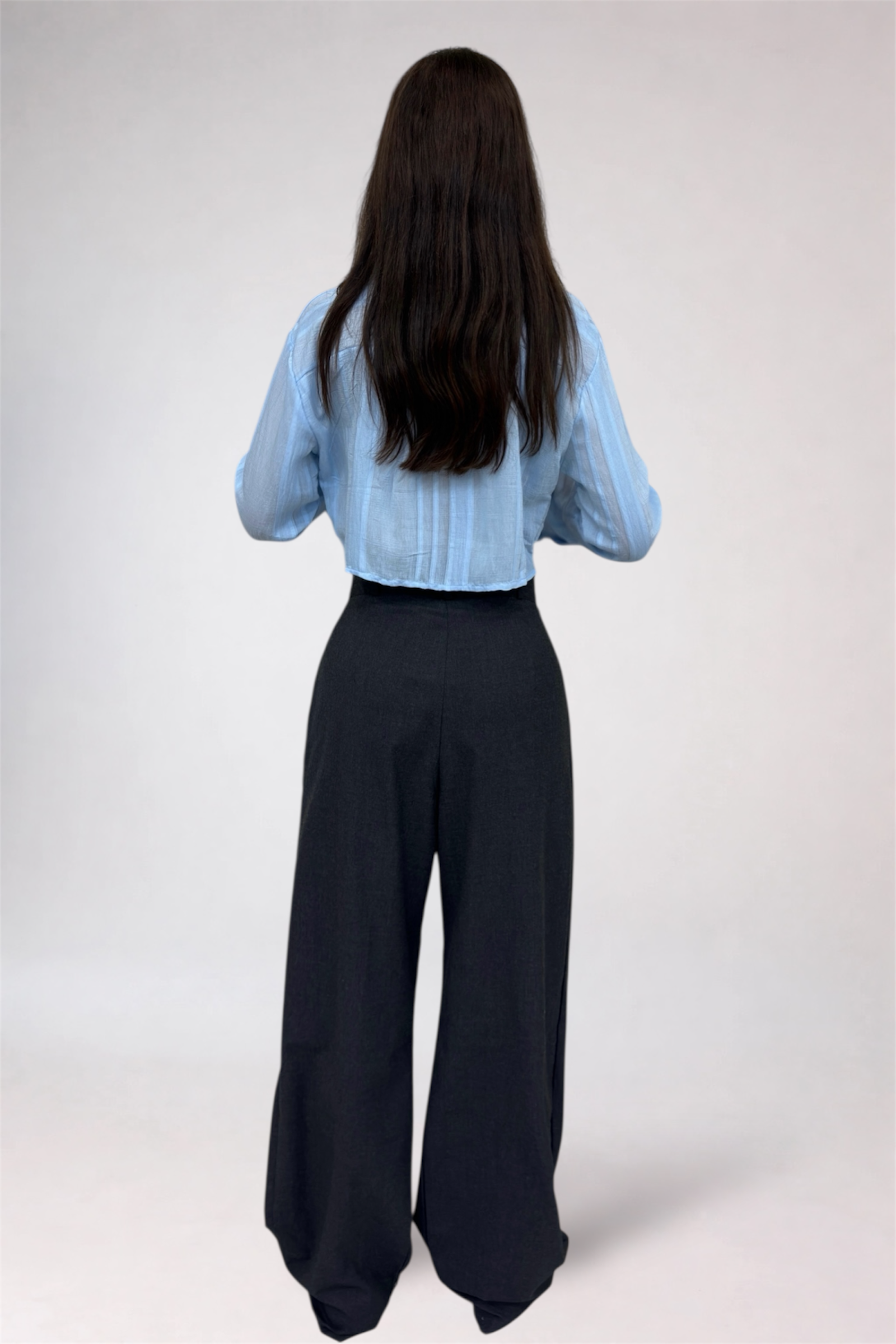 Person wearing a light blue blouse and black pants on a white background