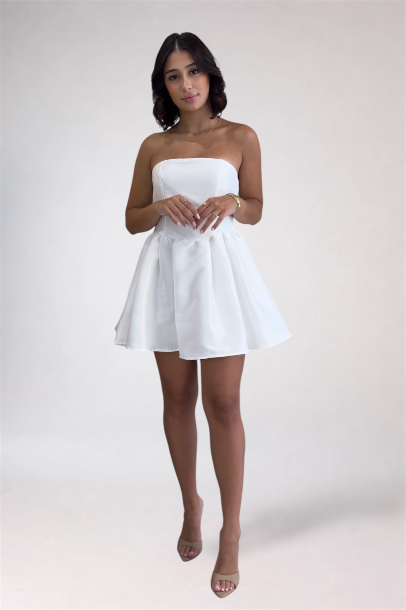 Woman wearing a white strapless dress on a plain background