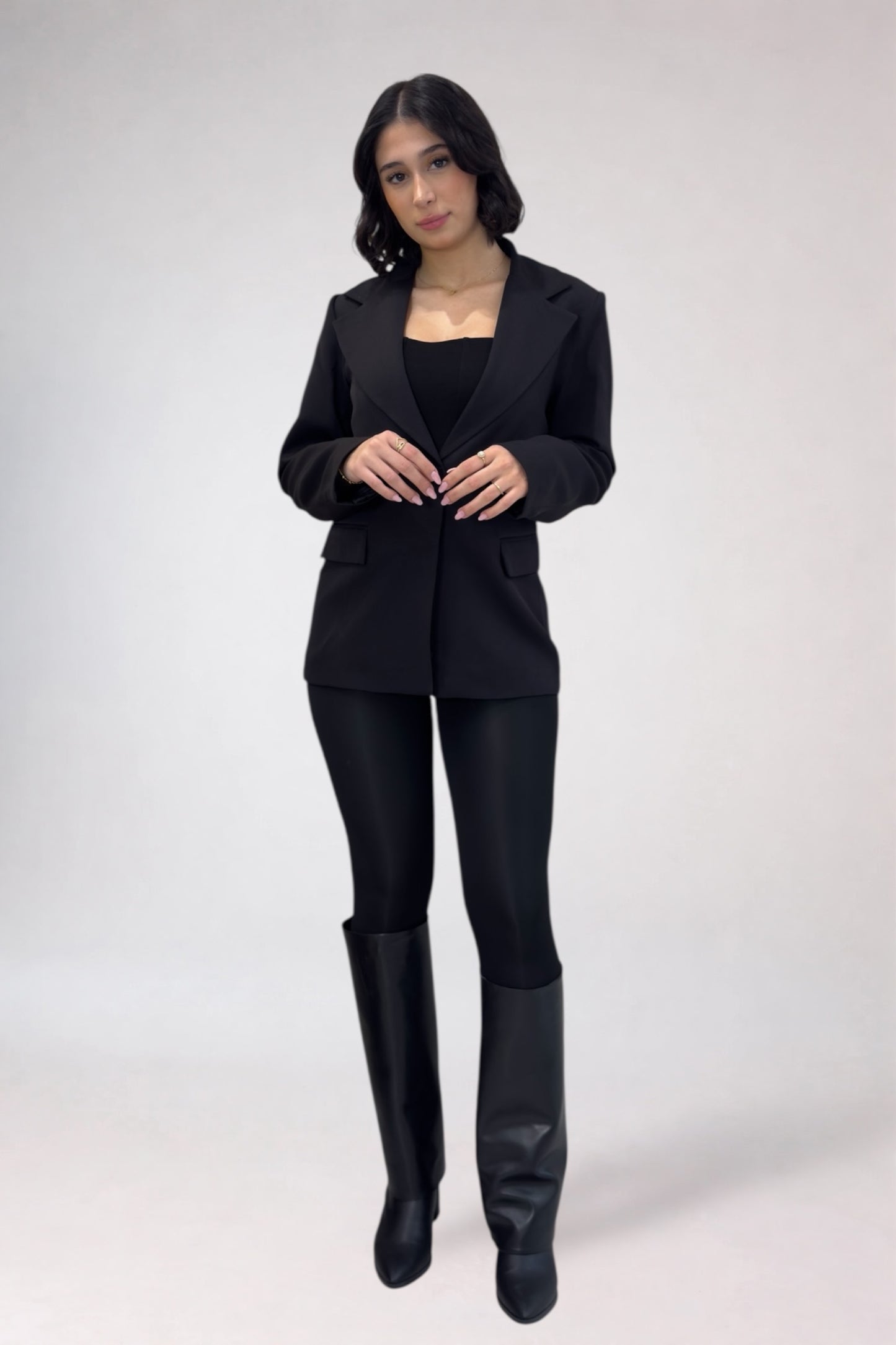 Woman wearing a black suit with black boots on a white background