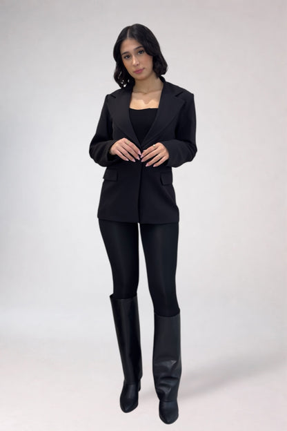 Woman wearing a black suit with black boots on a white background