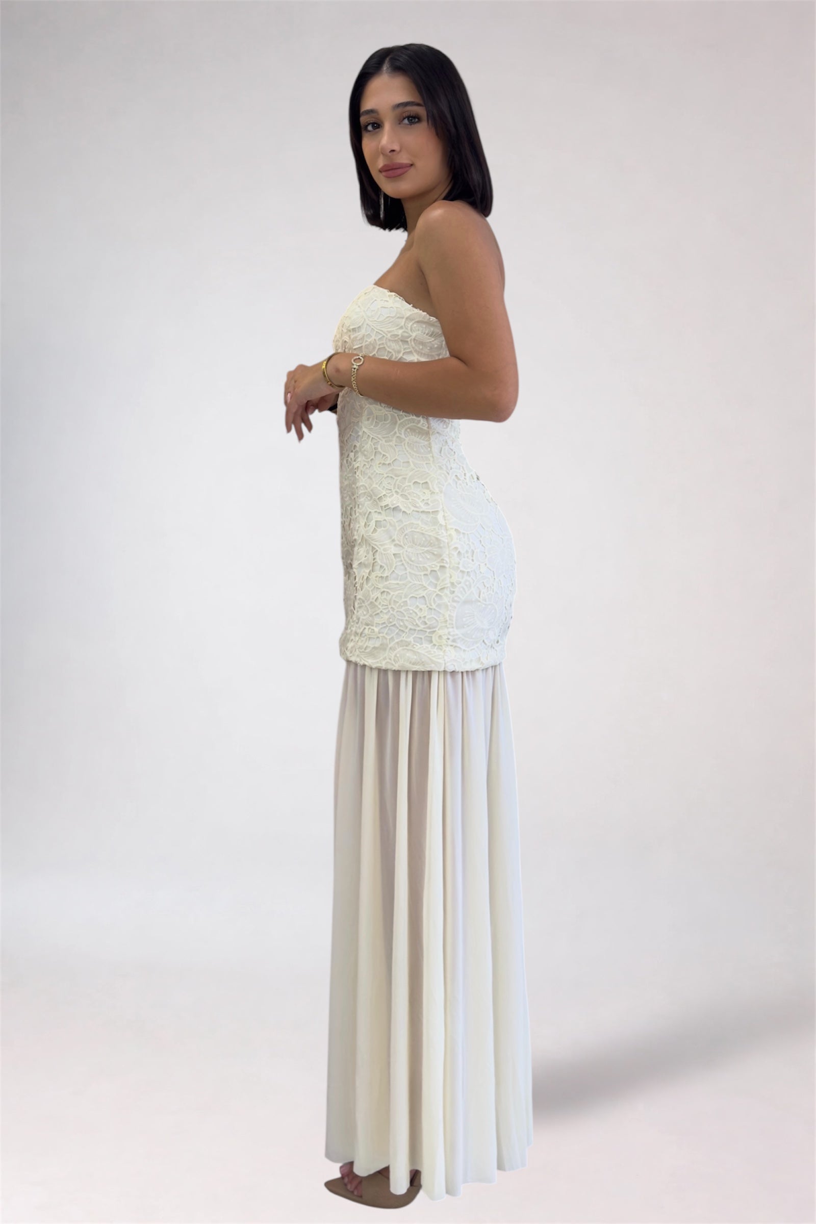Woman wearing a strapless white top and beige skirt on a plain background