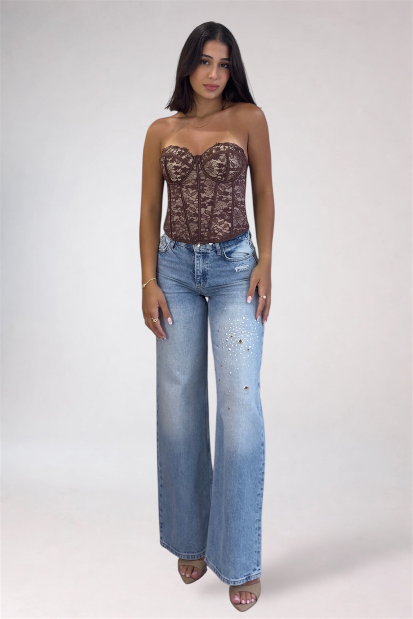 Woman wearing a lace top and blue jeans on a white background