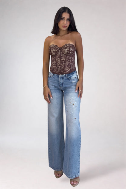 Woman wearing a lace top and blue jeans on a white background