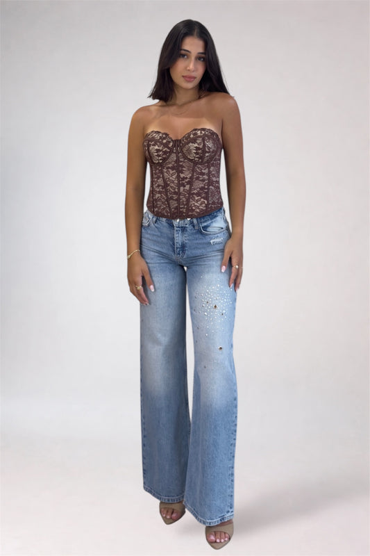 Woman wearing a lace top and blue jeans on a white background