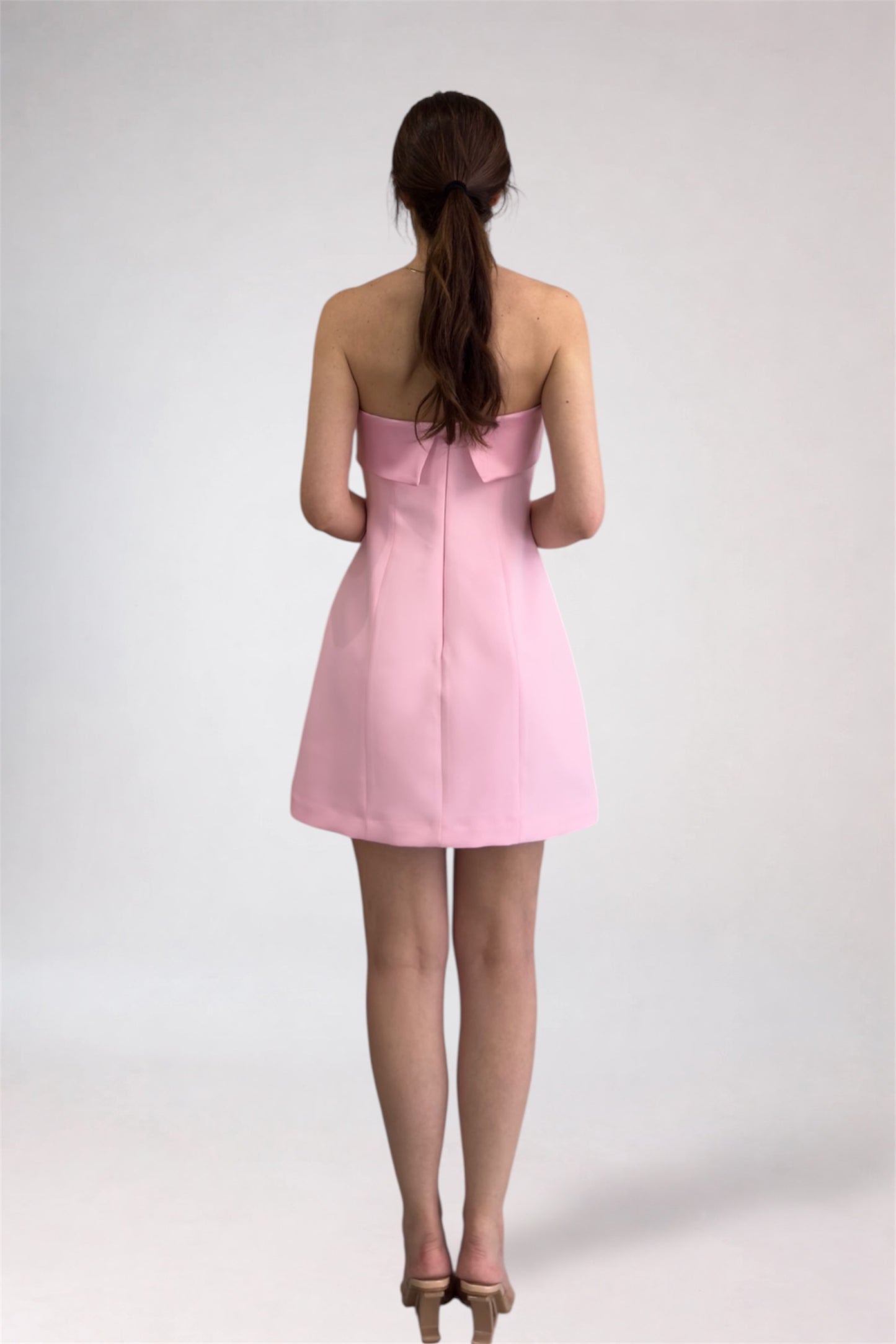 Woman wearing a pink strapless dress on a white background