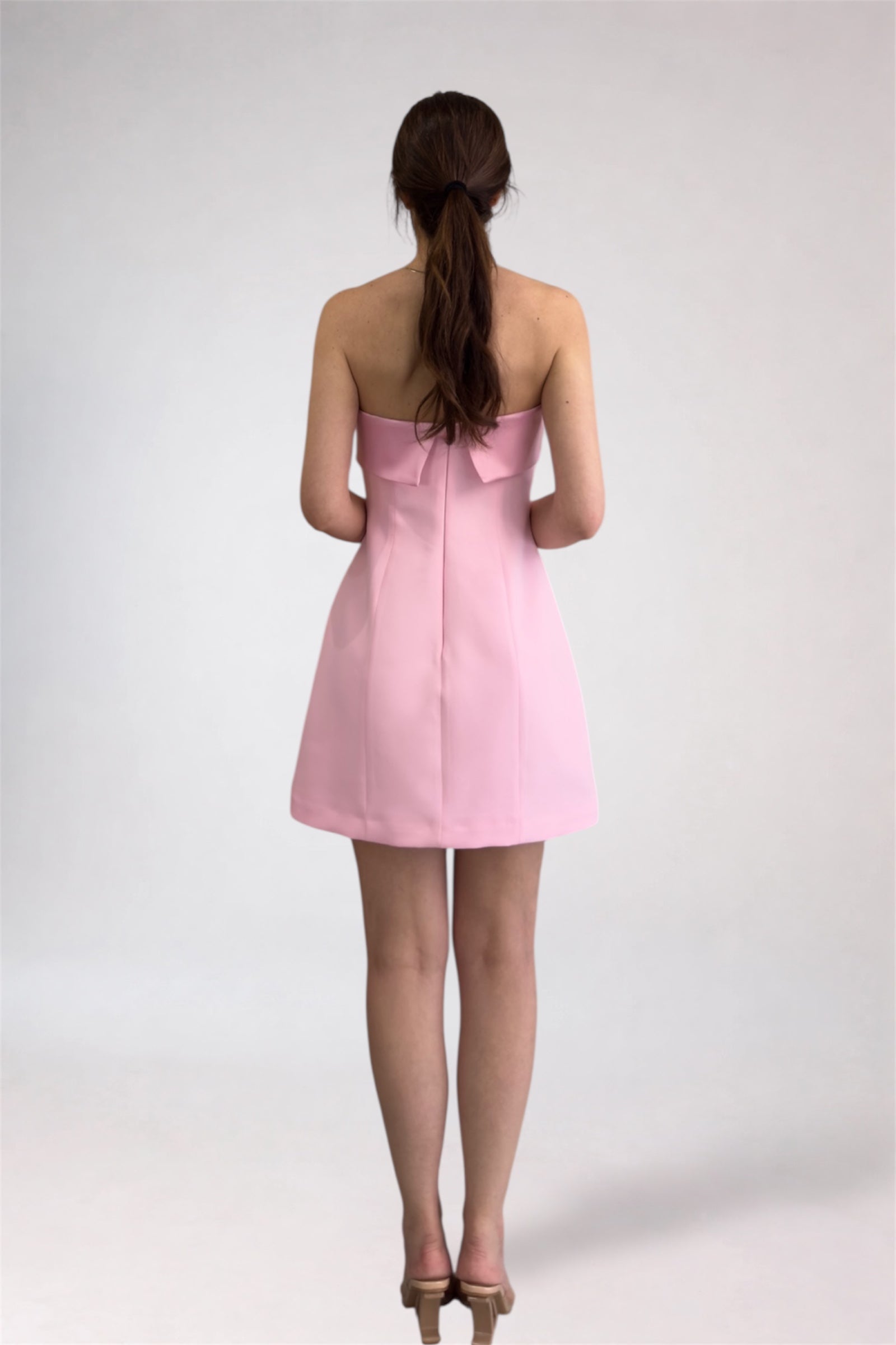 Woman wearing a pink strapless dress on a white background