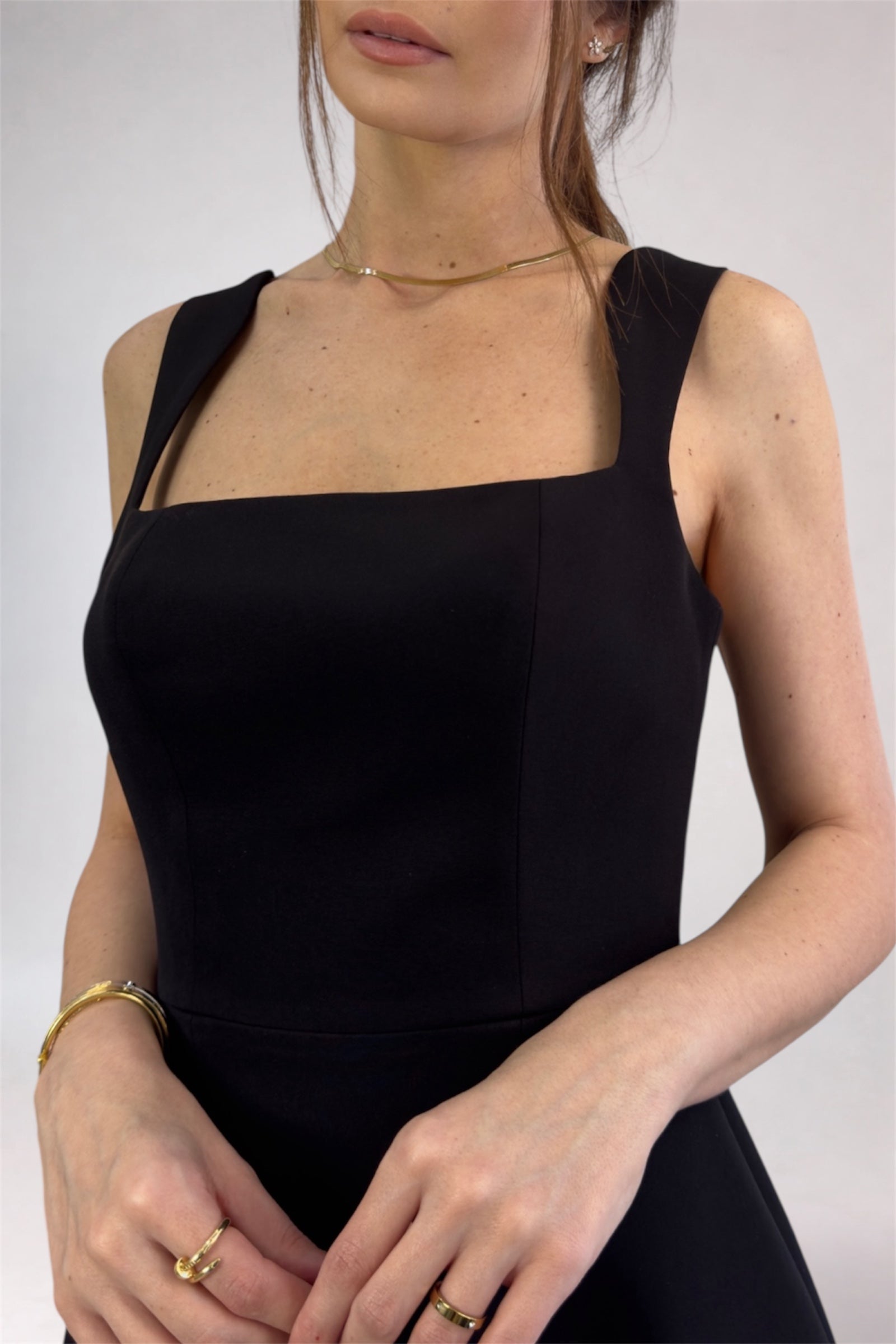 Woman wearing a black sleeveless dress against a plain background