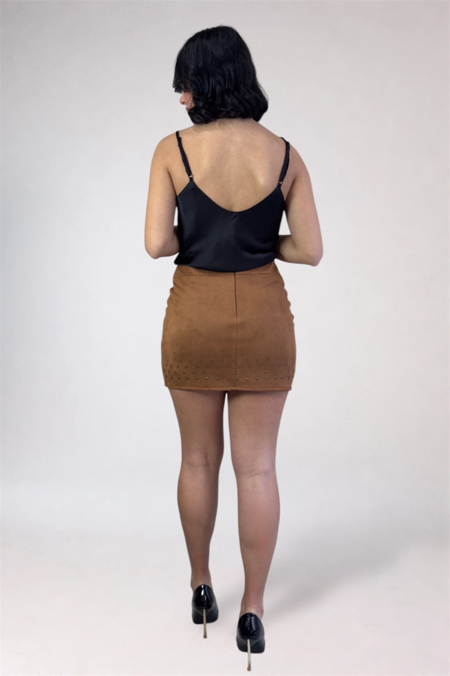 Person wearing a black top and brown skirt on a white background