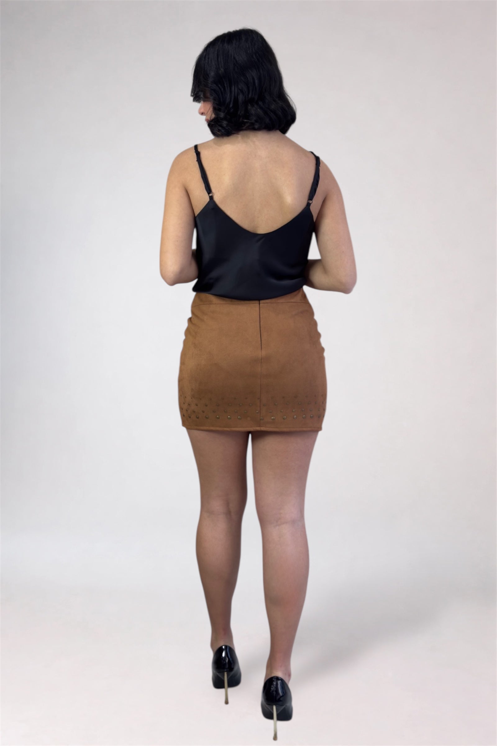 Person wearing a black top and brown skirt on a white background
